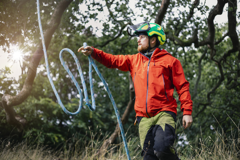 Tree surgeon wearing safety helmet throwing rope for tree surgery