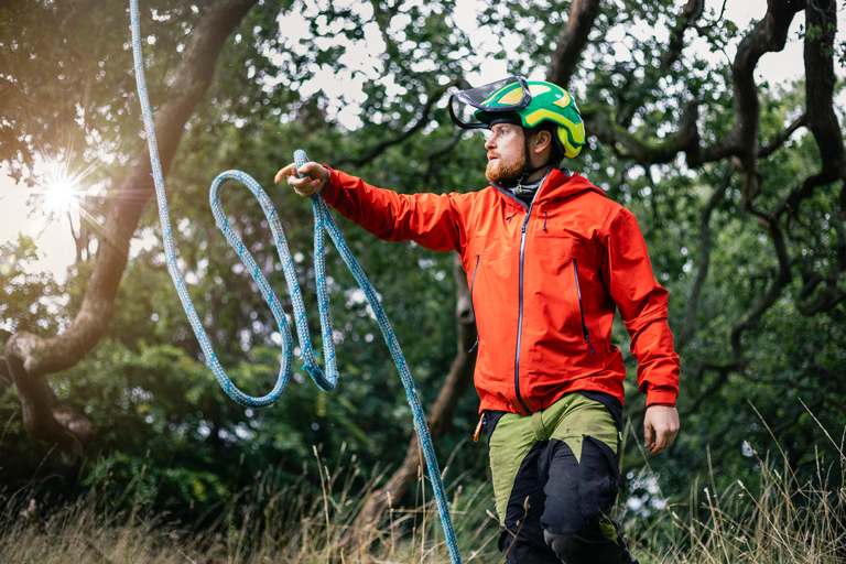 Tree surgeon wearing safety helmet throwing rope for tree surgery